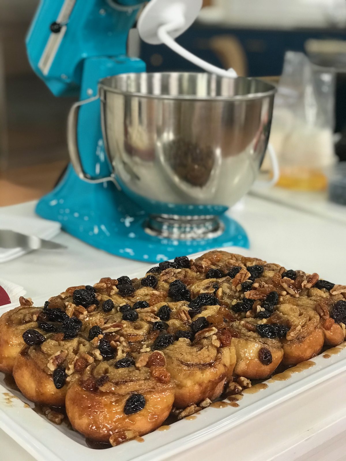 platter of sticky buns in front of Ocean Drive colored KitchenAid 5qt Artisan Stand Mixer fitted with dough hook