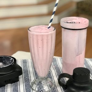 strawberry milkshake in glass with straw, KitchenAid personal blending jar off to the side