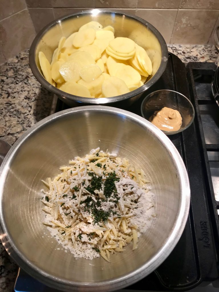 Preparation for making Creamy Potatoes Au Gratin - Bowl with peeled and slice potatoes, bowl with cheese mixture and the mustard measured and in a small bowl