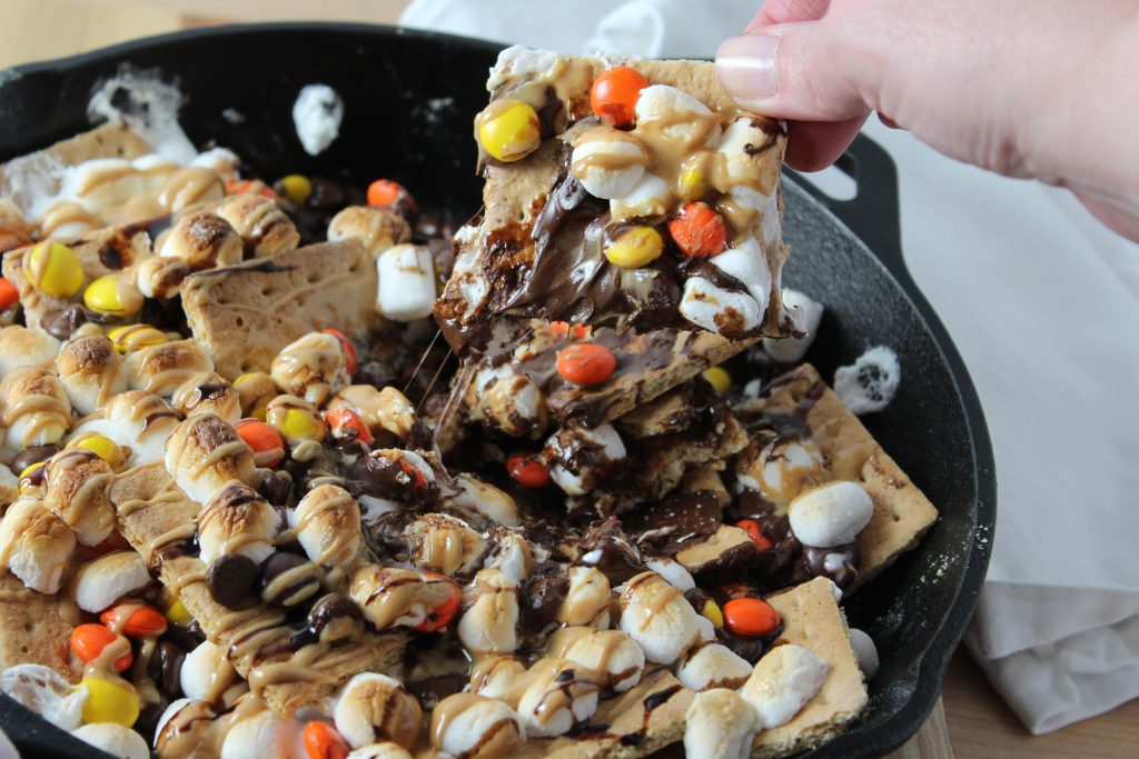 Peanut Butter Skillet S'mores Nachos in Cast Iron Skillet portion being pulled out