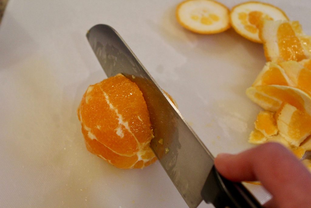 Cutting orange segments. Santoku knife cutting along orange membrane.