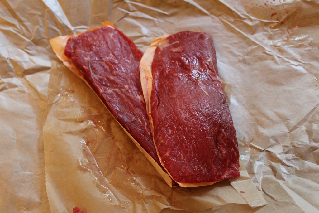 2 flat iron steaks laying atop butcher paper.