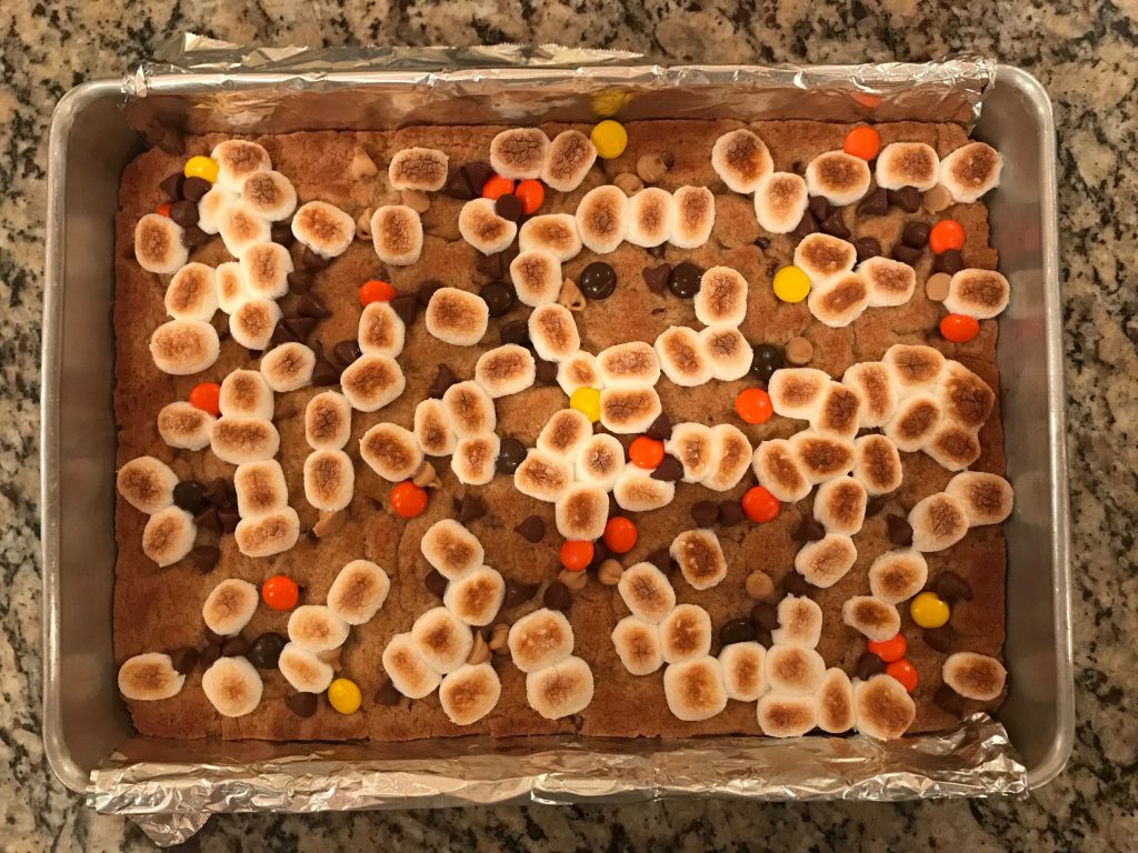 Peanut Butter S'mores Cookie Bars - 9x13x2-inch aluminum pan fitted with foil sling with baked dough being topped with broiled marshmallows