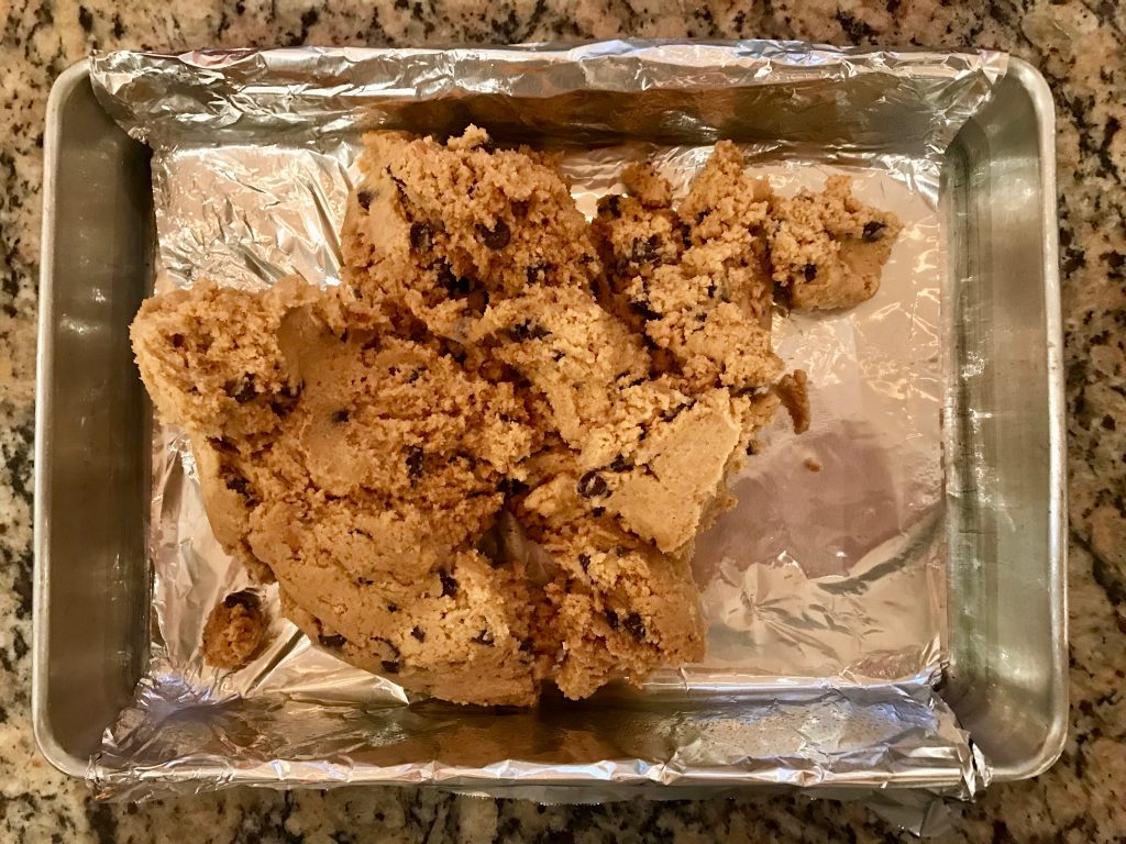 Peanut Butter S'mores Cookie Bars - 9x13x2-inch aluminum pan lined with foil sling and dough in center ready to be spread