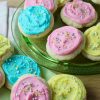 Cream Cheese Sugar cookies frosted in light pink, yellow and blue with nonpareil sprinkles - arranged on green glass platter