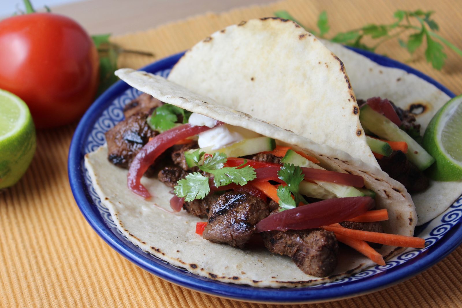 2 beef tacos with homemade flour tortillas on blue plate