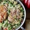 All-Clad Large Skillet filled with fettuccini in Parmesan cream sauce, with broccoli, red pepper and topped with sliced grilled chicken