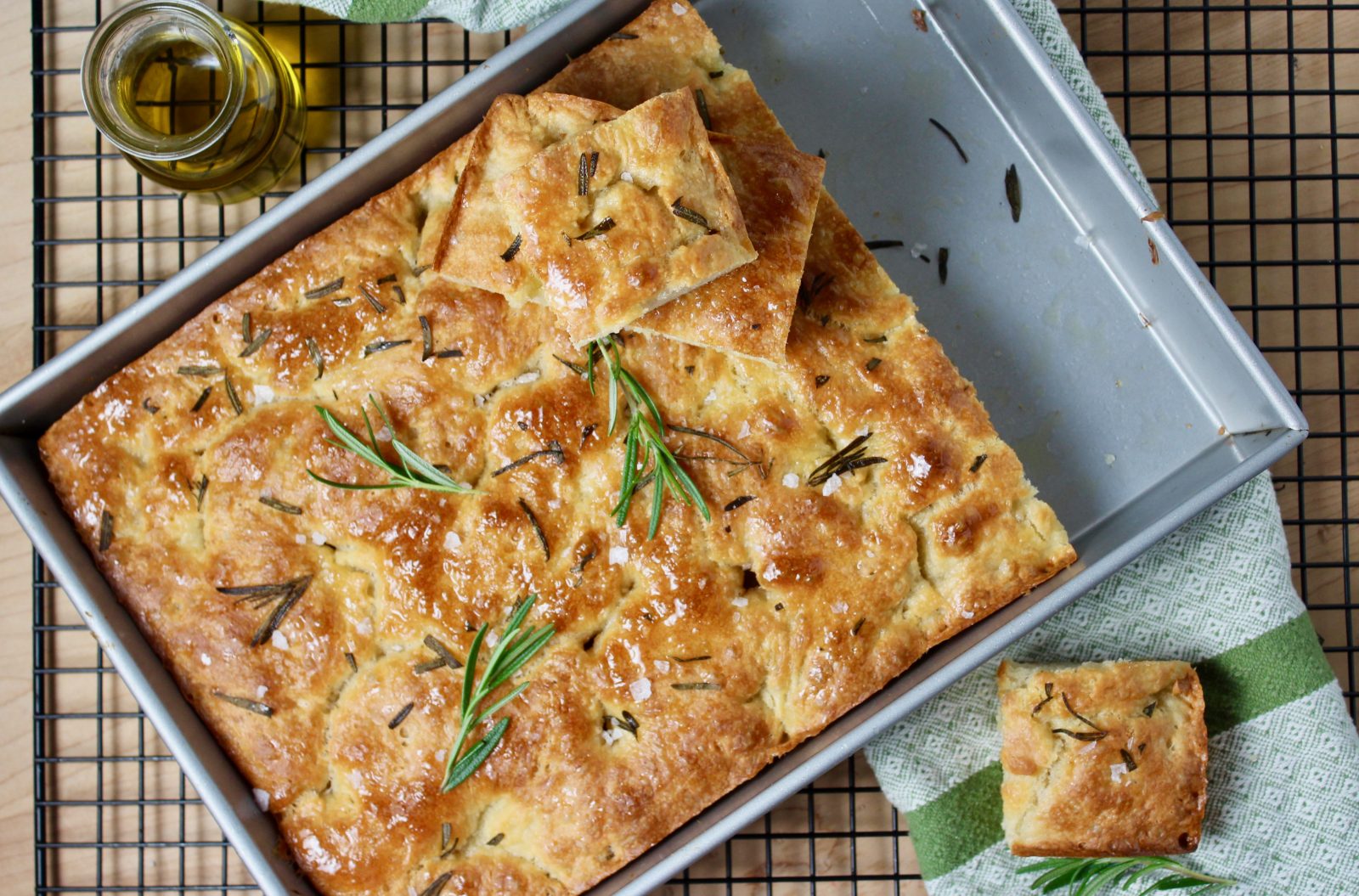 overhead photo of rosemary focaccia bread in 13 x 9 metal baking pan, topped with rosemary