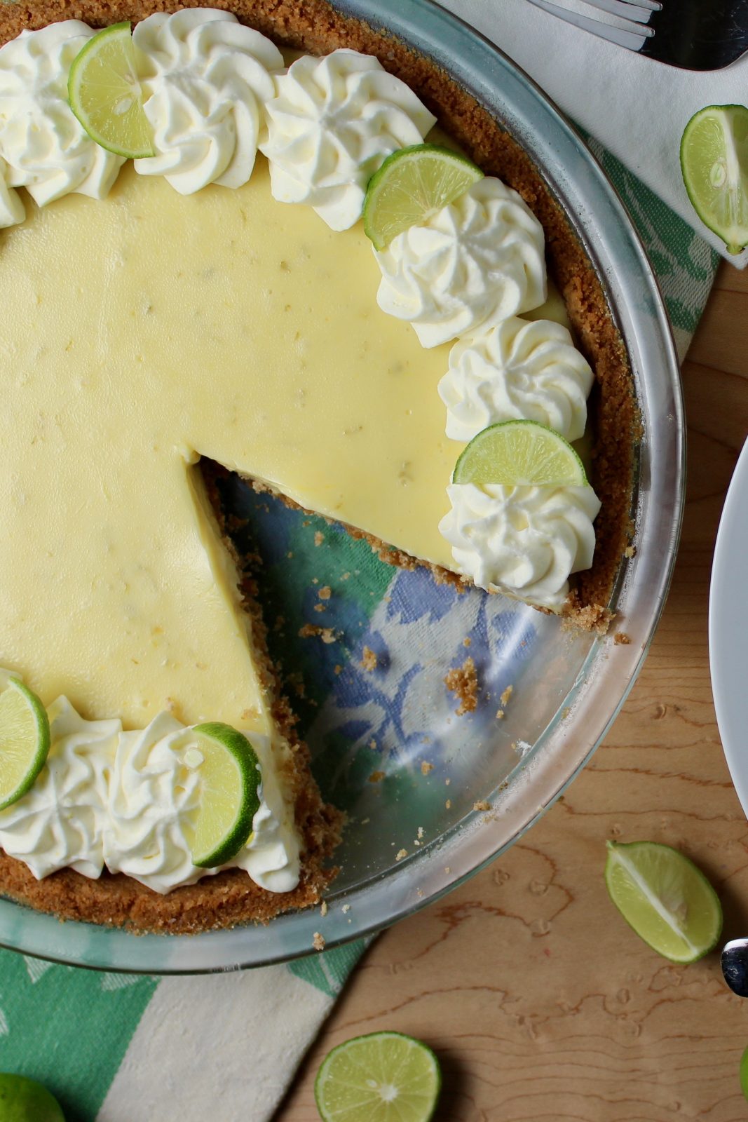 Key Lime Pie with slice cut. garnished with whipped cream rosettes and key lime slices