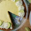 Key Lime Pie with slice cut. garnished with whipped cream rosettes and key lime slices