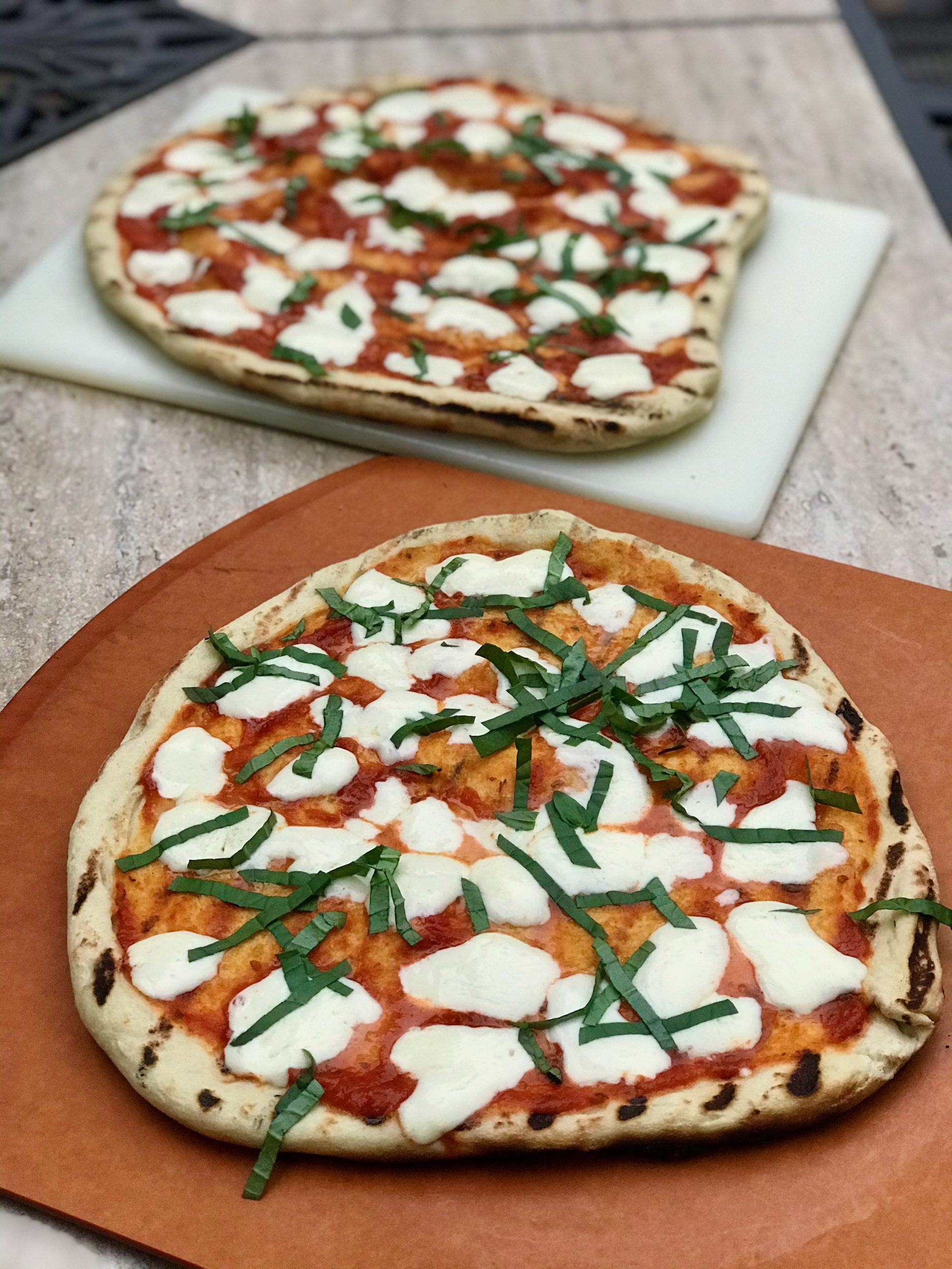 two grilled margarita pizzas on table