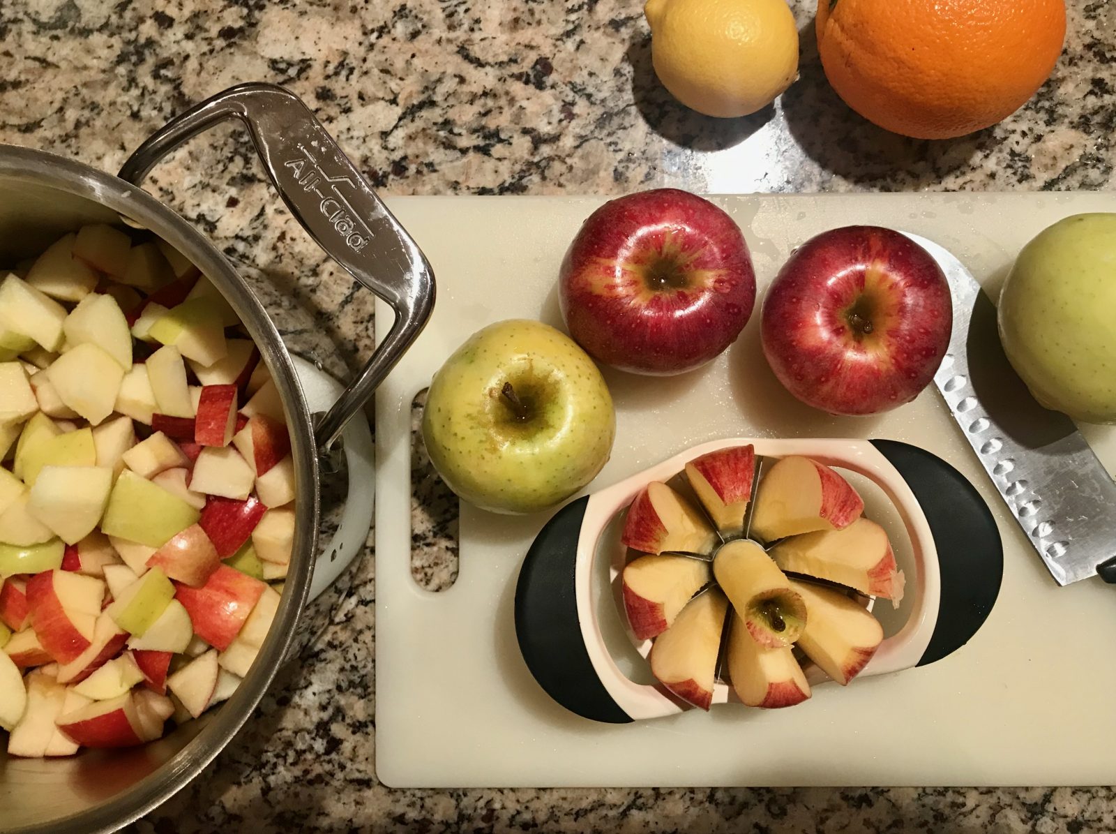 cutting board, apple slicer, apples, pot with chopped apples for applesauce