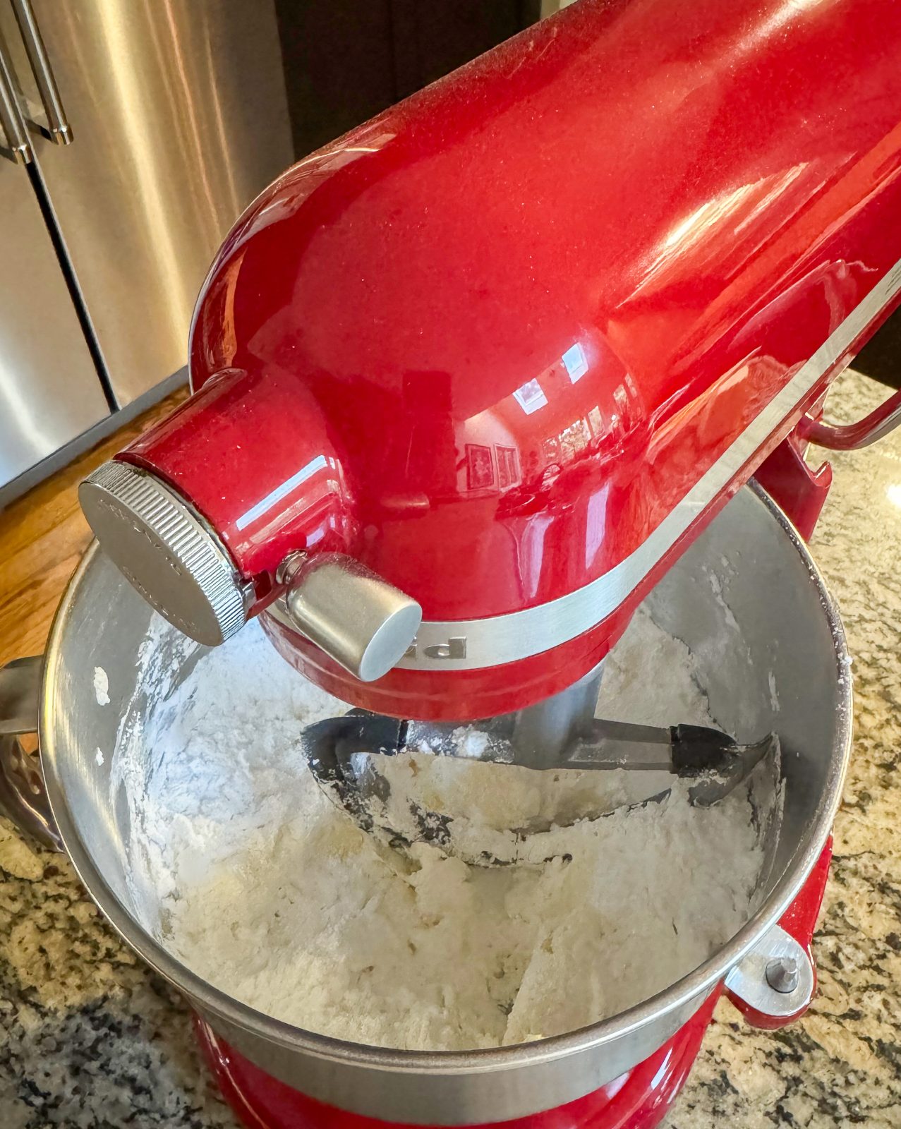 Recipe Photo for Less Sweet American Buttercream Frosting.  Red KitchenAid Stand Mixer mixing together butter, sugar and salt.
