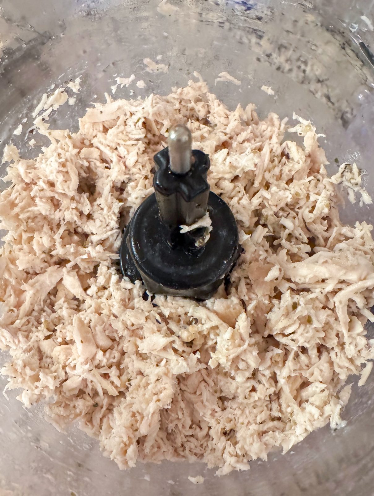 Shredded cooked chicken breast in KitchenAid 7-cup food processor.