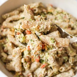 recipe image for creamy honey mustard pasta salad. Overhead shot of rigatoni, chopped broccoli and red pepper, shredded cheddar cheese in a creamy honey mustard greek yogurt dressing.