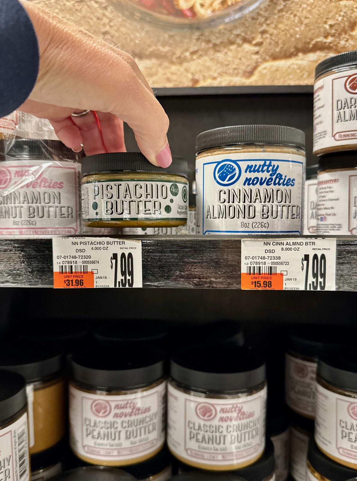 Selecting a jar of pistachio butter from the nut butter shelf at the grocery store
