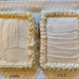 Comparison photo of Stella Parks American Buttercream vs Milk Street 123 Frosting showing 2 half sheet cakes frosted each frosted with the different buttercream with piping around the top edge.  the one on the left is more golden in color, the one on the right is whiter.
