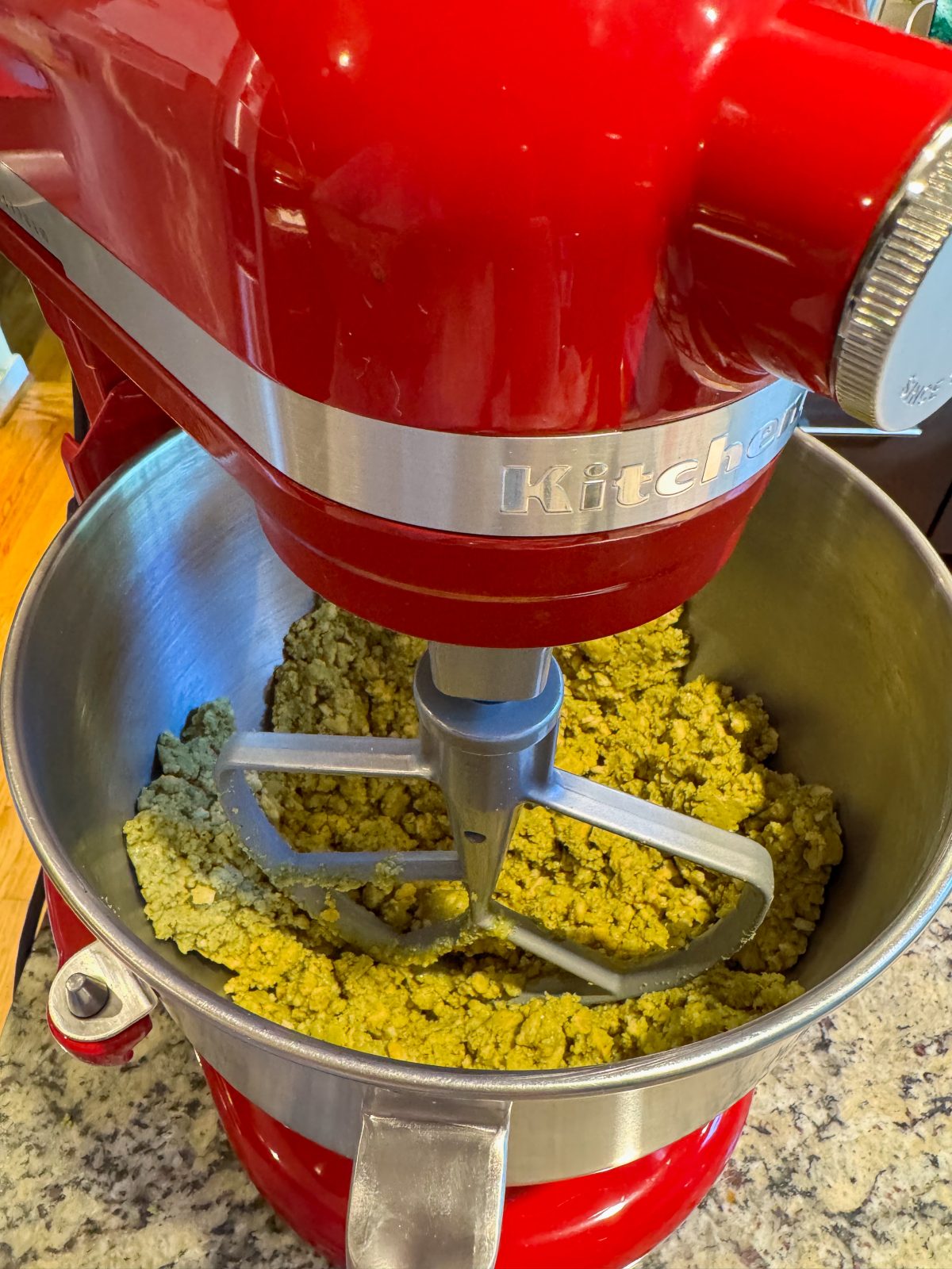 Recipe Photo for Dubai Style Pistachio Oreo Truffles shows red KitchenAid Bowl lift stand mixer with crumbly green mixture in the bowl.