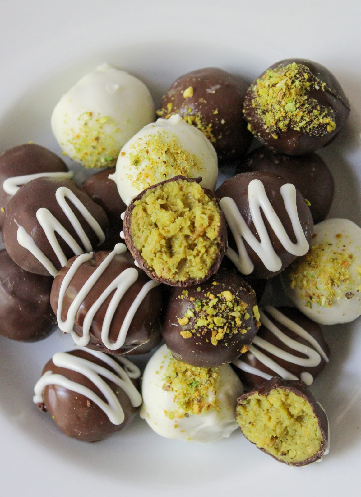 Dubai Style Pistachio Oreo Truffles Recipe Beauty Photo. Recipe Beauty Shot of Dubai Oreo Truffles. Close up overhead shot of a Bowl of dark, white and milk chocolate truffles decorated with pistachio dust or white chocolate drizzles in white shallow bowl.