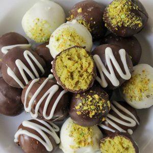 Dubai Oreo Truffles Recipe Beauty Photo. Recipe Beauty Shot of Dubai Oreo Truffles. Close up overhead shot of a Bowl of dark, white and milk chocolate truffles decorated with pistachio dust or white chocolate drizzles in white shallow bowl.
