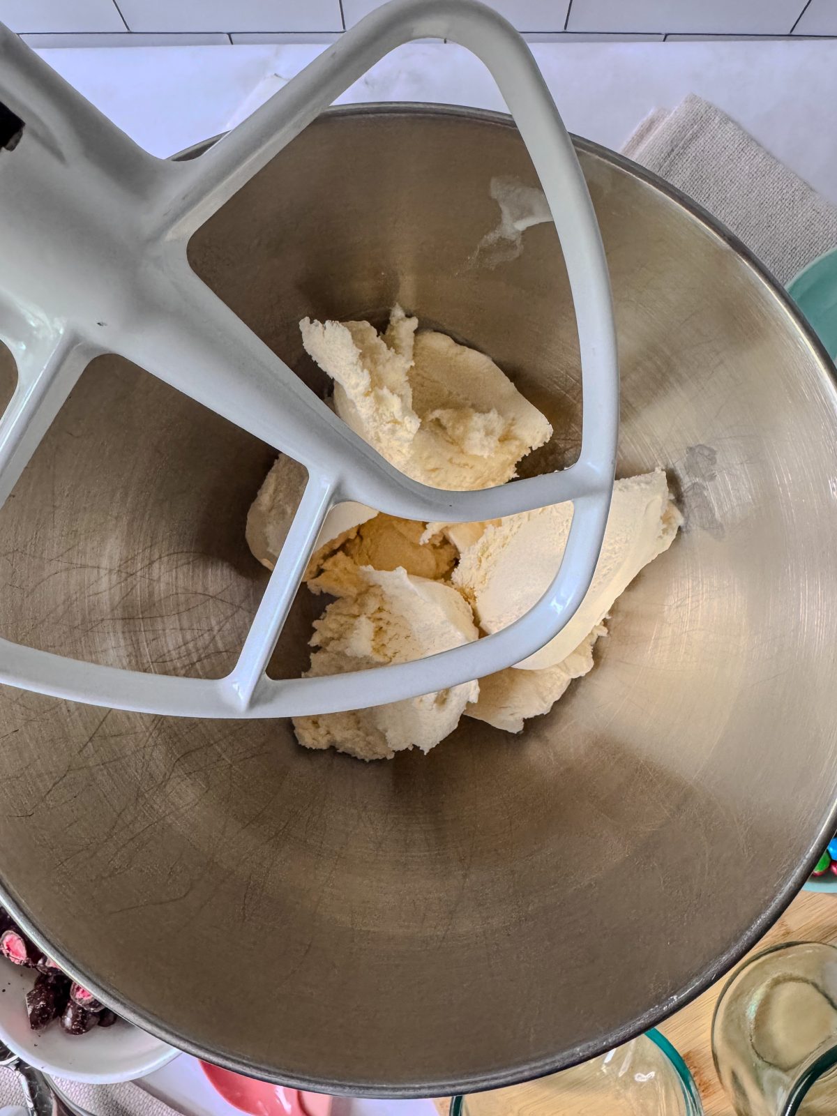 Recipe Process Photo for How to Make a Blended Blizzard Style Ice Cream Treat with Your Stand Mixer showing overhead shot of 6 scoops of vanilla ice cream inside a stainless steel KitchenAid 5qt stand mixer bowl with the white flat beater above.
