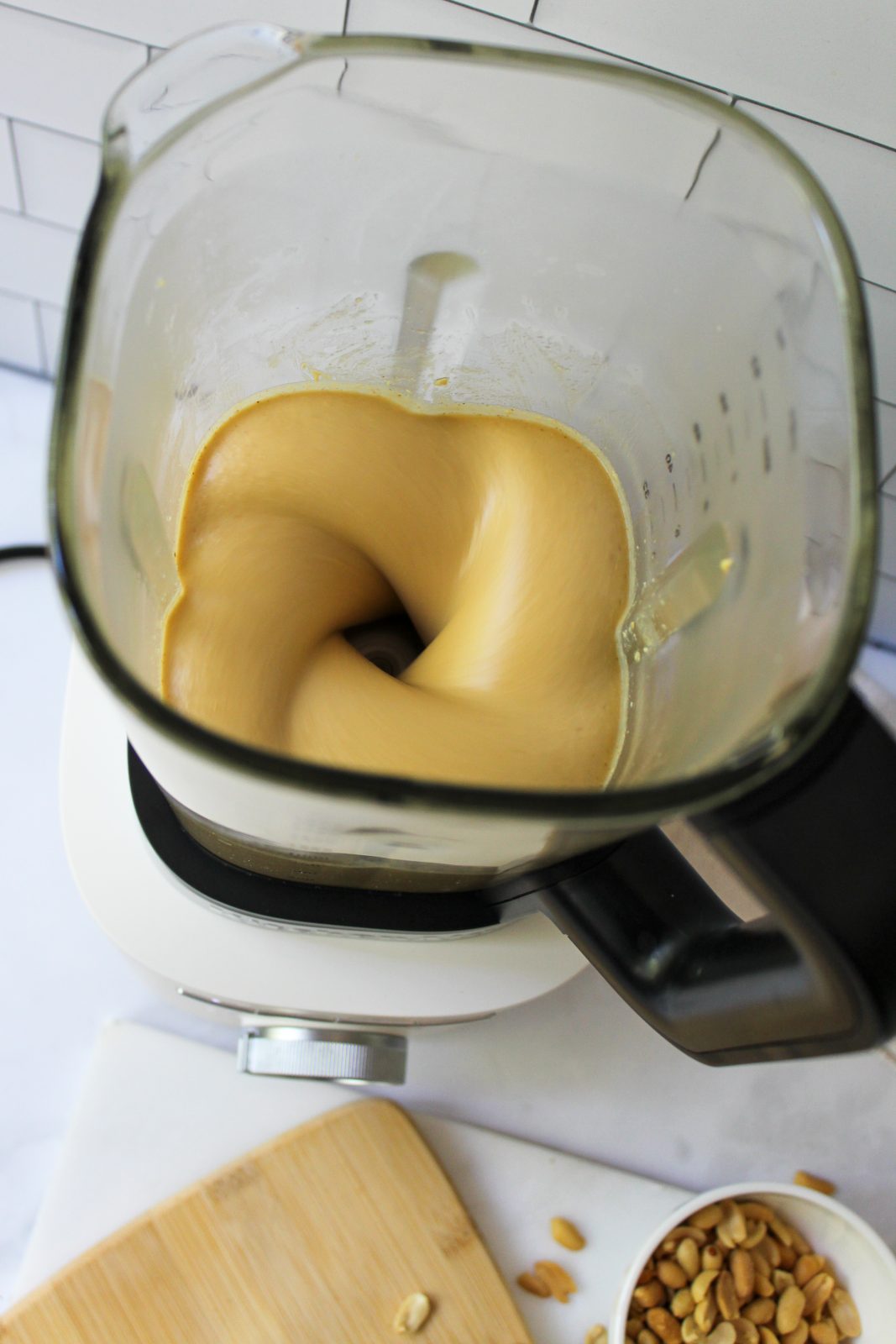 Recipe Photo for Homemade Peanut Butter. Shows peanut butter blending in a Porcelain White KitchenAid Pure Power Blender with Glass Jar. You can see the peanut butter making a 4-part swirled vortex inside the glass blender jar.